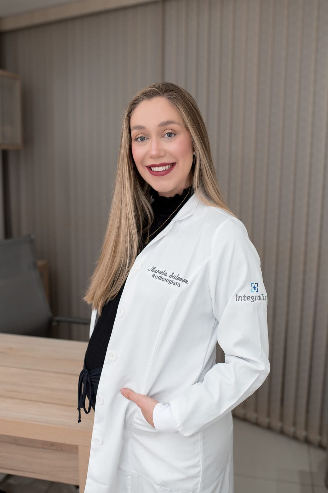 Dra. Marcela Salomon, médica radiologista, de jaleco branco no consultório de ultrassonografia em Nova Friburgo